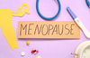 Menopause, surrounded by medication, a paper uterus, and a thermometer.